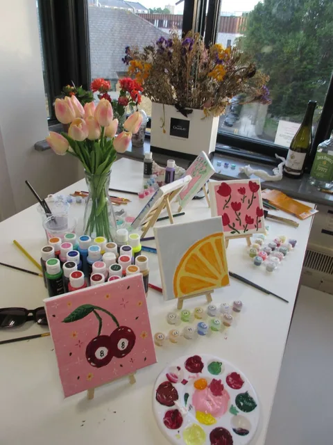 Table d'atelier avec peintures, pinceaux et petites toiles